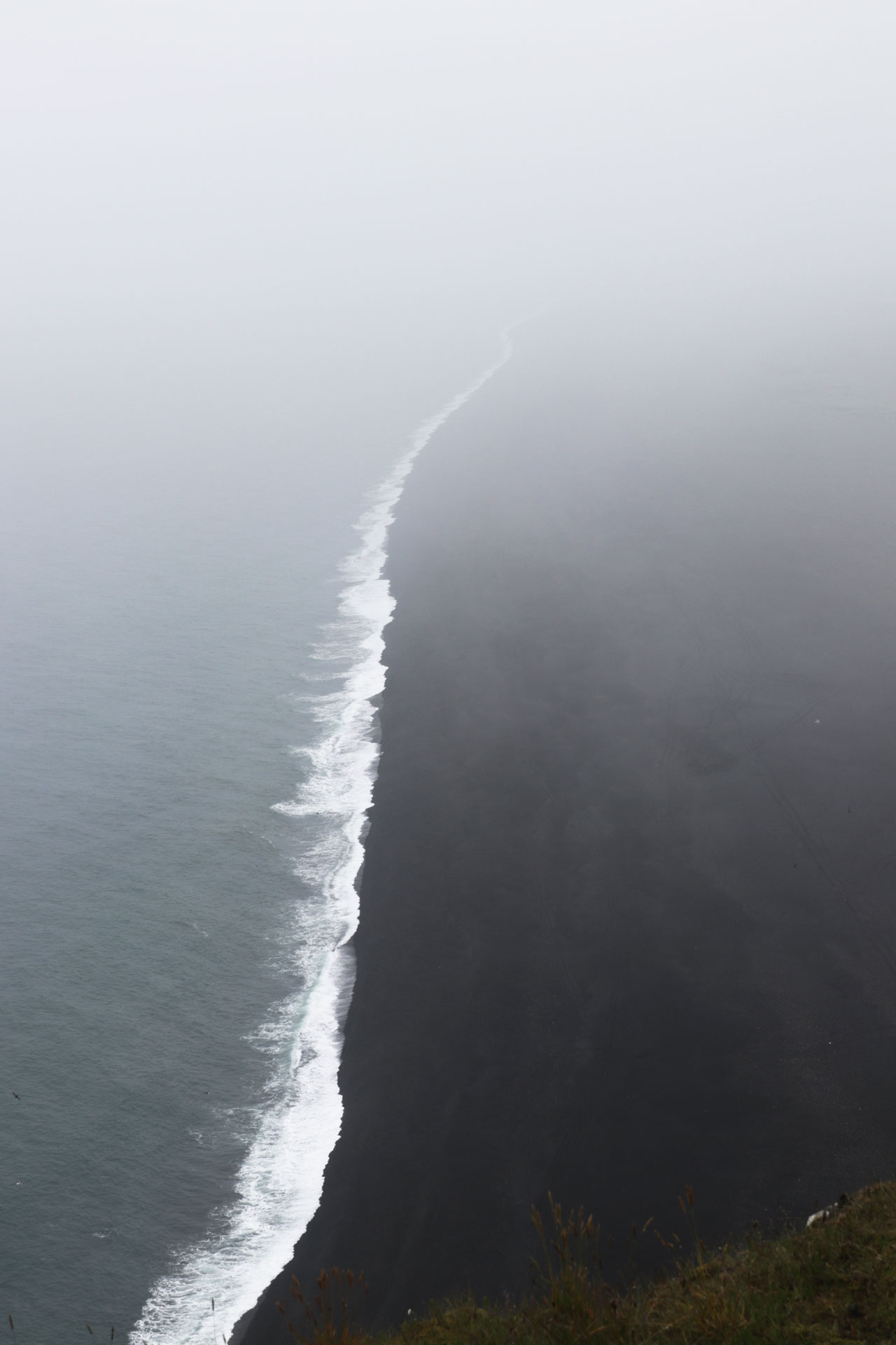 Blick von den Klippen gen Sünden auf den schwarzen Strand und das Meer